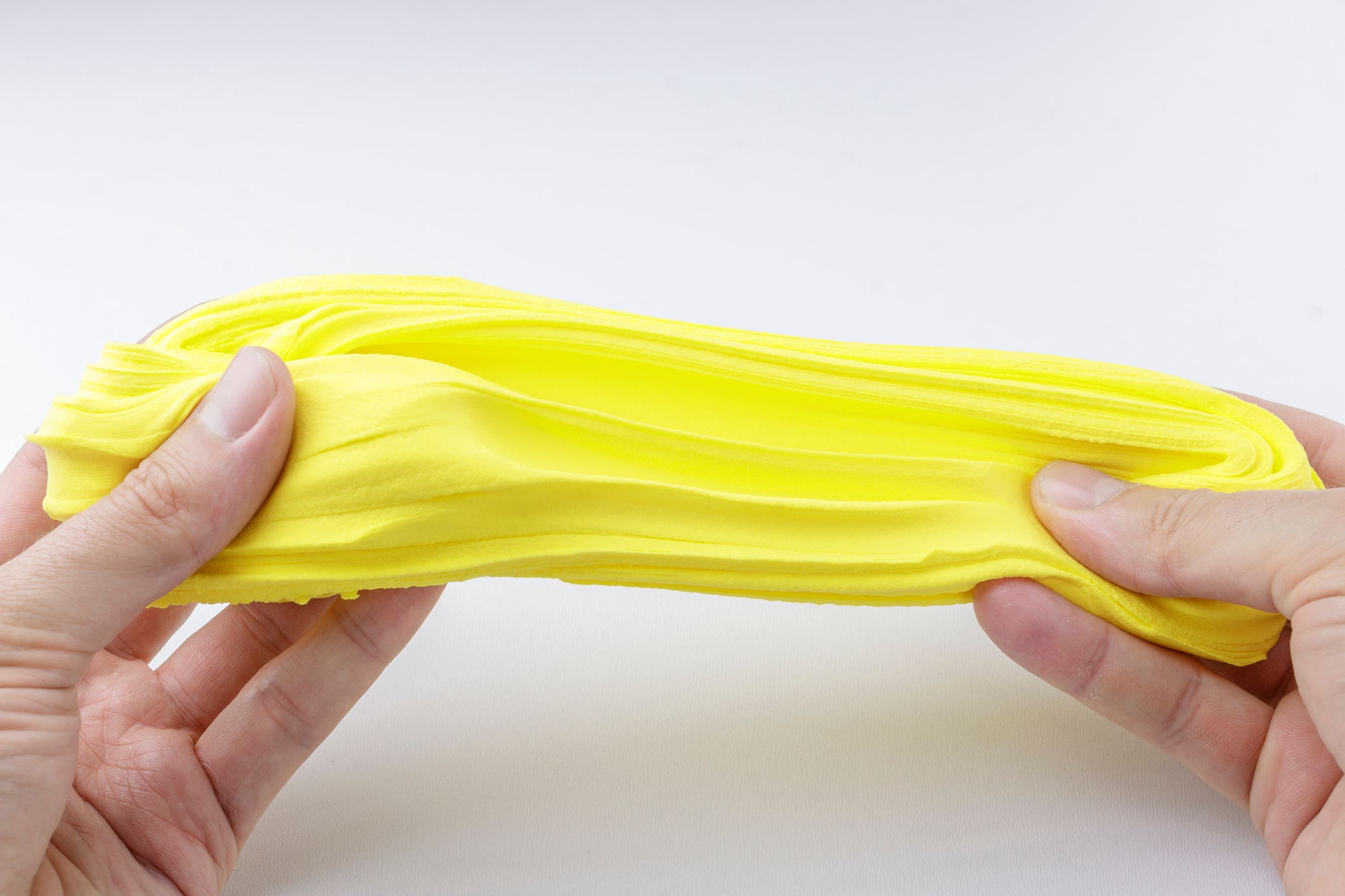 Hands stretching yellow silly putty